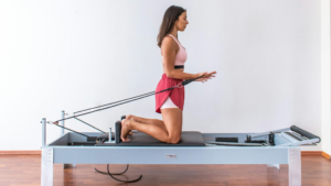 Mulher pratica pilates no reformer, aparelho que trabalha força, controle do core e postura.