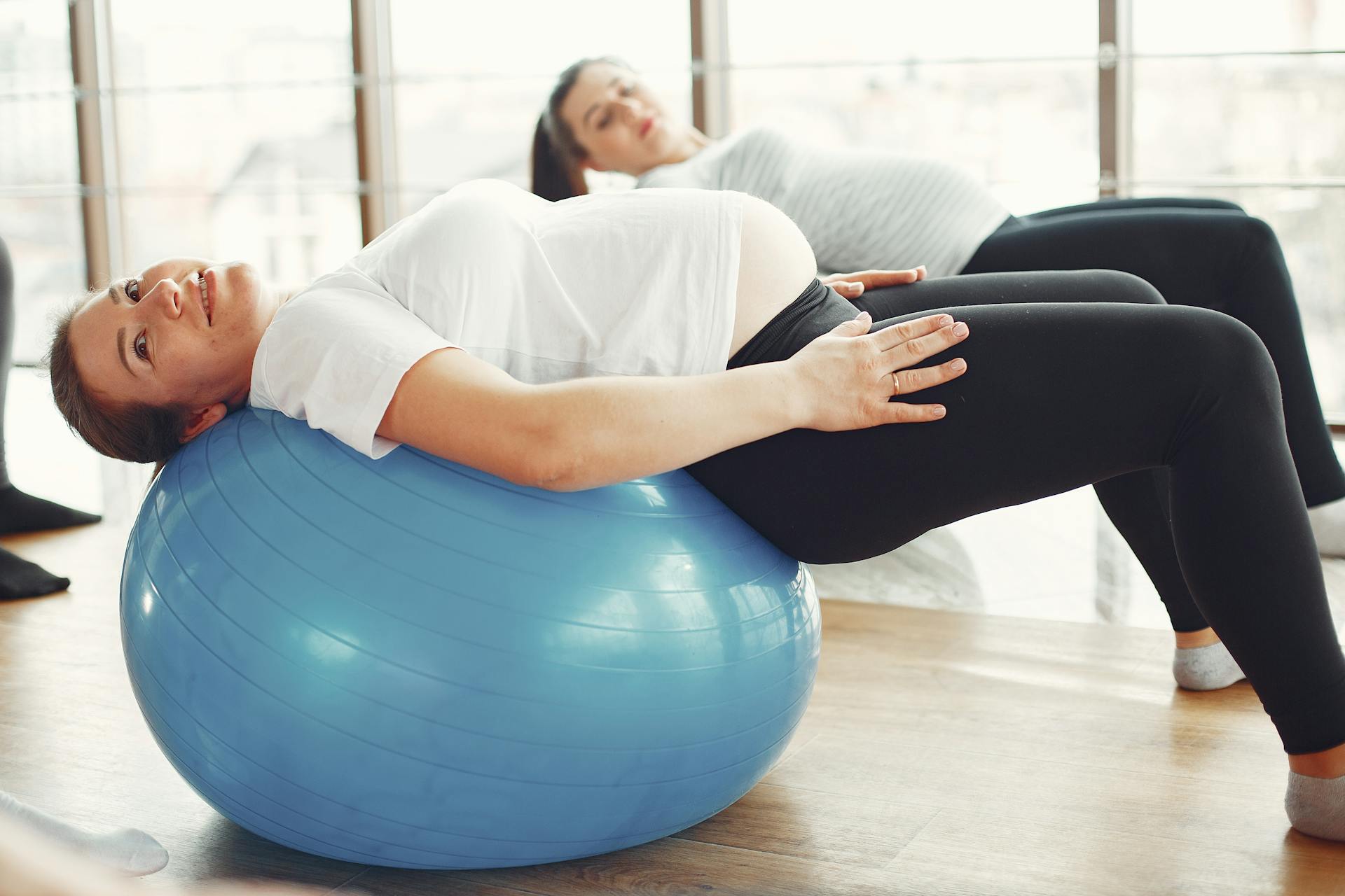 Gestante faz exercício com bola de pilates durante aula de atividade física para gravidez.