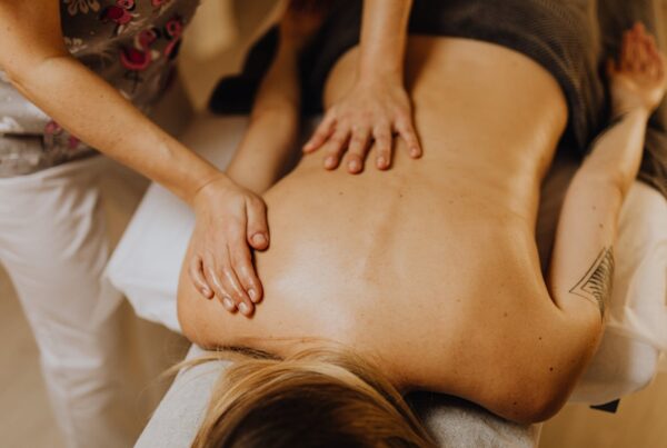 Profissional realizando massagem relaxante nas costas de uma mulher em ambiente de bem-estar